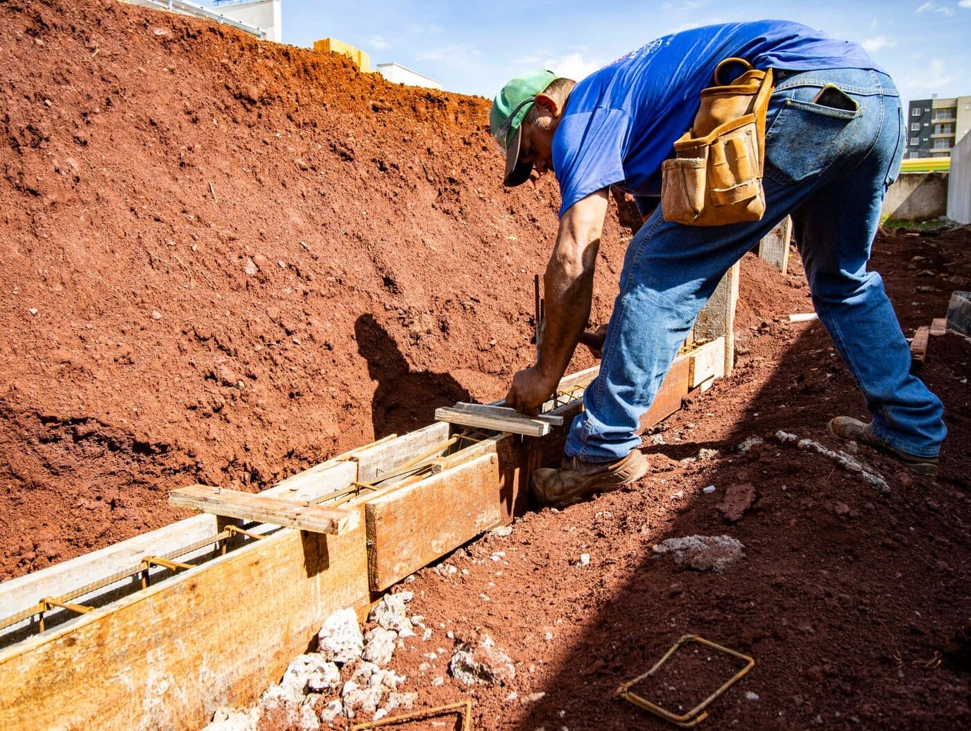 A worker forming and pouring a house foundation footing